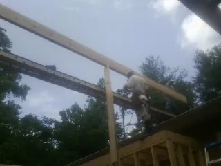 Carpenter setting a ridge beam over a new addition frame — Ice Dam Removal by Roofing Brothers in Batson