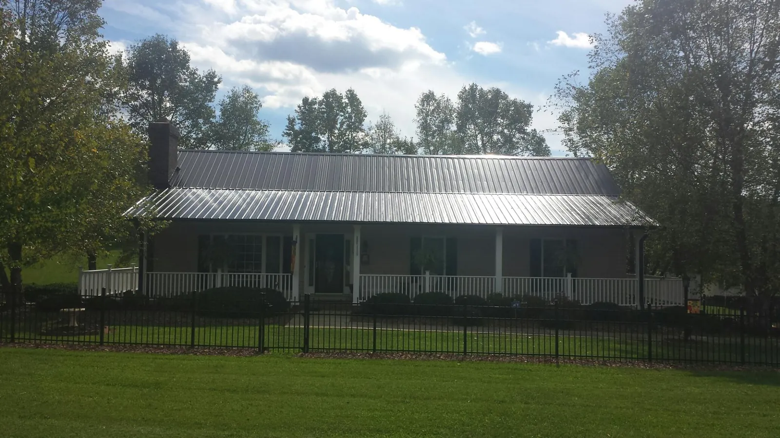 Gray metal roof on a brick ranch with a full width front porch — Gutter Guard Installation work by our crew in Batson